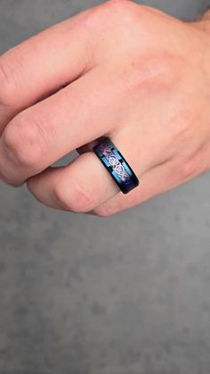 a man's hand wearing a black and blue ring