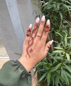 a woman's hand with henna tattoos on her left wrist and ring finger