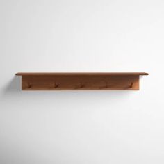 a wooden shelf mounted to the wall with three pegs on each side and two holes in the middle