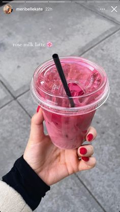 a person holding up a pink drink in their hand