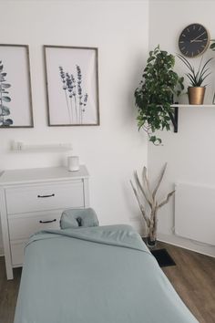 a bed sitting in a bedroom next to a white dresser and potted plant on top of it