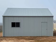 a small metal building sitting on top of a dirt field