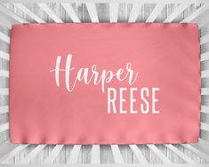 a pink pillow with the words harper reesee on it in white lettering against a wood background