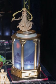 a statue of a woman standing on top of a table next to a clock and figurine