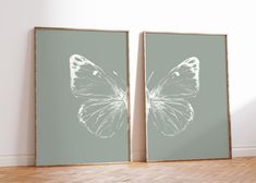 two framed pictures on the wall with a butterfly drawn in white and light green paint