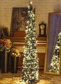 two christmas trees are lit up in front of a piano