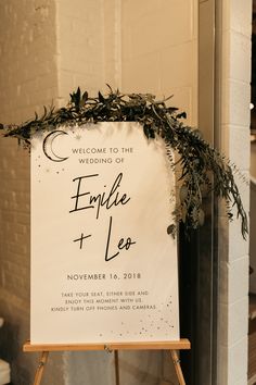 a welcome sign with greenery on it for an outdoor wedding in the wintertime