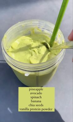 a hand holding a spoon in a cup filled with green liquid and the words pineapple avocado spread over it