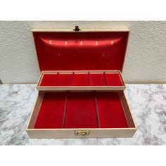 an open box with red velvet lining and gold trim on the inside is sitting on a marble countertop