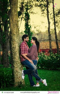 a man and woman leaning against a tree in the park during an engagement photo session