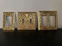 three golden frames sitting on top of a black table