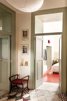 an open door leading to a bedroom with a red chair in the corner and pictures on the wall