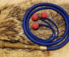 two red balls on a blue rope next to a brown and black animal fur rug