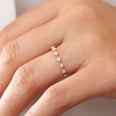 a woman's hand wearing a gold ring with three diamonds on it and the middle finger