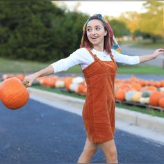 a woman in an orange dress holding a pumpkin