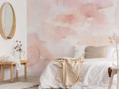 a bedroom with pink watercolor paint on the wall and white bedding, two small tables