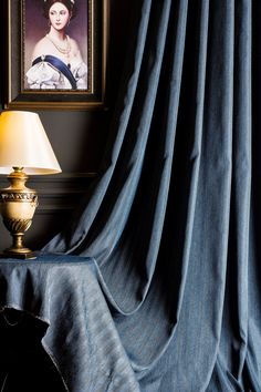 a lamp sitting on top of a table next to a blue drape covered wall