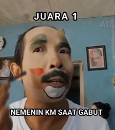 a man with his face painted to look like an orange and white clown, has the words juara 1 written on it