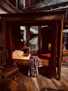 a bed sitting on top of a wooden floor next to a red curtained window