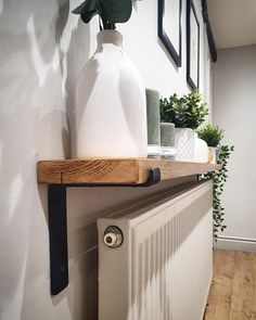 a white vase sitting on top of a wooden shelf next to a radiator