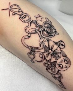 a black and white photo of a tattoo design on the leg with scissors, keys, stars and hearts