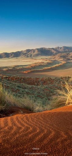 a desert landscape with mountains in the distance and blue sky above it, as seen from an overlook point on a sunny day