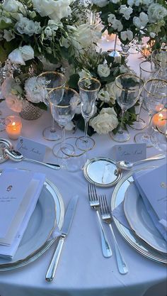 the table is set with silverware and white flowers