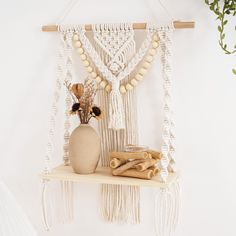 a white macrame hanging from a wall next to a vase with flowers