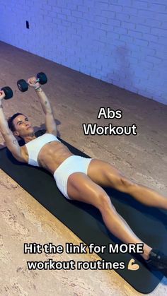 a woman laying on top of a black mat holding two dumbbells