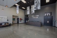 an empty lobby with signs hanging from the ceiling and pictures on the wall above it