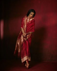 a woman in a red and gold sari is posing for the camera with her hand on her hip