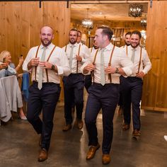 a group of men standing next to each other in front of a wooden wall with chandeliers