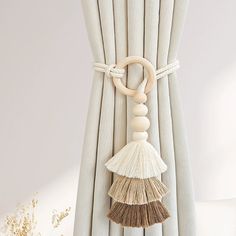 a white curtain with tassels hanging from it's side and a ring on the end