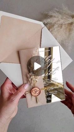 a person is holding an envelope with a card and some feathers on the inside of it