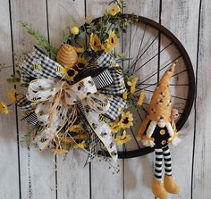 a bicycle wheel decorated with sunflowers and a scarecrow doll hanging on it