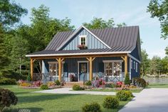 a small blue house with porches and flowers in the front yard on a sunny day