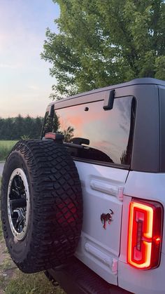 the rear end of a white pickup truck with its lights on and large tire arches