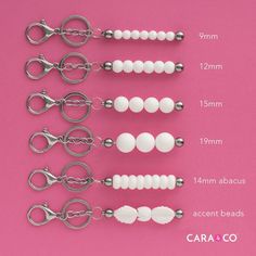 six pairs of scissors with white beads and silver handles on a pink background, labeled cara & co