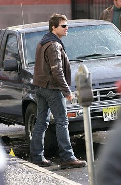 a man standing in front of a black truck next to a fire hydrant on the street