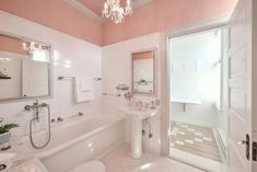 a bathroom with pink walls, white fixtures and a chandelier hanging from the ceiling