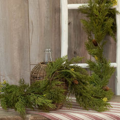 a basket filled with pine cones and greenery next to a window