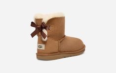 We added sweet, silky bows to your little one's favorite boot but kept the super-soft sheepskin feel they love. Built to move the way kids do, each boot features a rocker-bottom shape for a barefoot feel and our super-lightweight outsole for traction and durability. Pair with the same style in our women's sizes for cute mini-me moments. Pair with the same style in our women's sizes for cute mini-me moments.This product was made in a factory that supports women in our supply chain with the help o Mini Bailey Bow Uggs Outfit, Bailey Bow Uggs Outfit, Uggs Mini, Ultra Mini Uggs, Ugg Boots With Bows, Cute Uggs, Ugh Boots, Brown Ugg Boots, Uggs With Bows