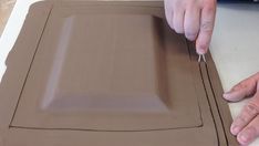 a person cutting out a piece of cardboard with scissors and glue on the edge of it