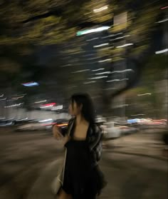 a woman is walking down the street at night with her hand in her pocket and looking back