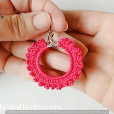 a hand holding a pink crochet keychain with a chain around it