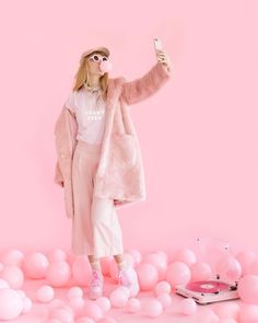 a woman in pink is taking a selfie with her cell phone while standing on balloons