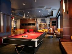 a pool table in the middle of a room with couches and chairs around it