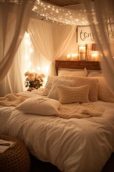 a bed with white sheets and lights on the headboard is lit up by candles