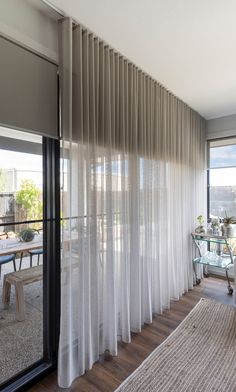 an open living room with sliding glass doors and white drapes on the windowsill