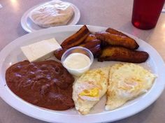 a white plate topped with breakfast foods on top of a table